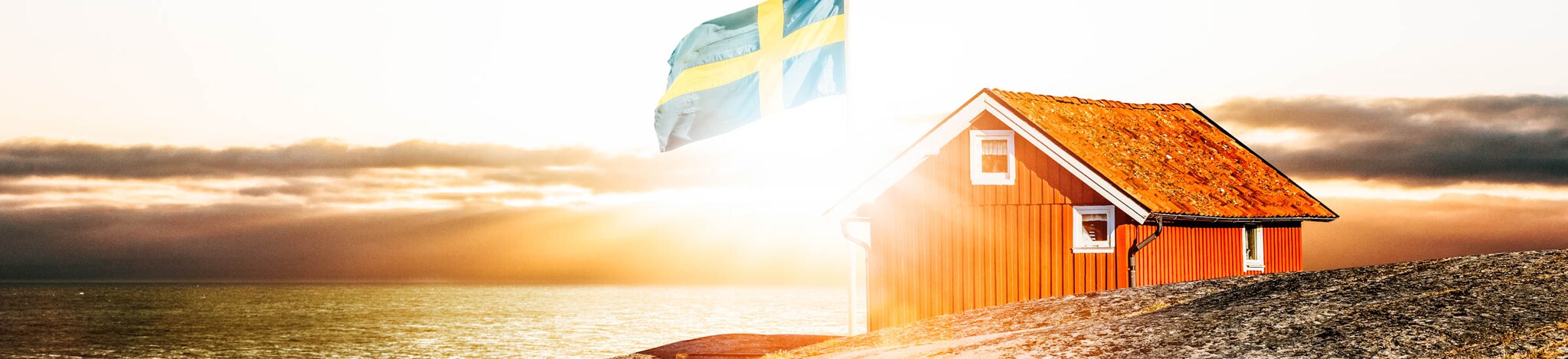 rotes Haus und Schweden-Flagge an der Küste – Familienurlaub in Schweden