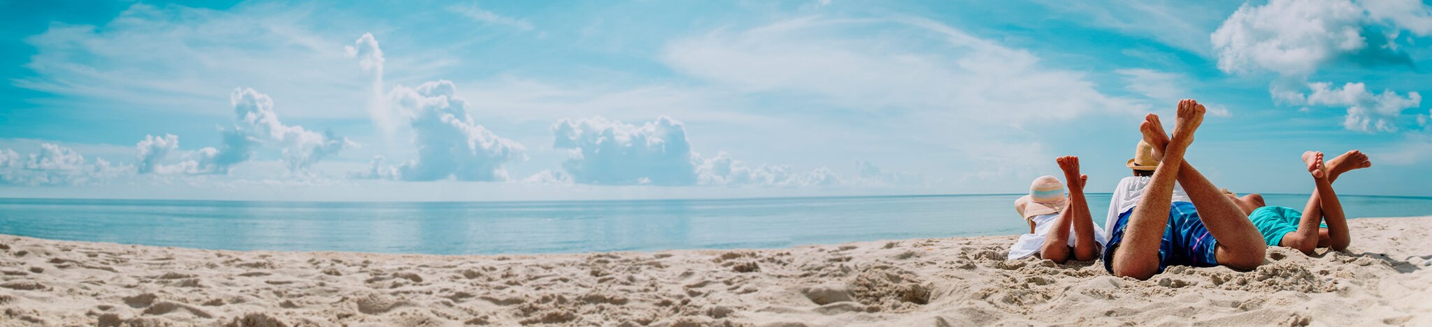 Familie liegt am Strand und schaut auf das Meer